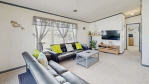 Ein modernes Wohnzimmer mit Sofa, Couchtisch, Fernseher und Essbereich.