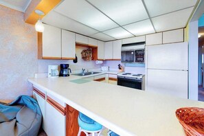 Une cuisine de taille réduite avec un îlot central, une cuisinière, un four à micro-ondes et un réfrigérateur.