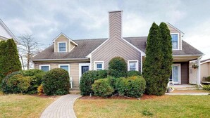 A residential house with a brick pathway leading to the entrance, surrounded by well-maintained hedges and a lawn. - Quiet Family Home 4 Blocks from the Beach/Boardwalk with Deck, WiFi & Fireplace (Ocean City)