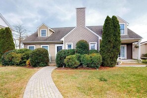 A residential house with a brick pathway leading to the entrance, surrounded by well-maintained hedges and a lawn. - Quiet Family Home 4 Blocks from the Beach/Boardwalk with Deck, WiFi & Fireplace (Ocean City)