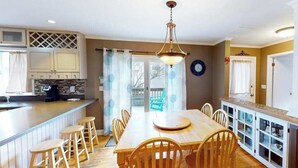 A kitchen with a wooden dining table, bar stools, and a pendant light. - Quiet Family Home 4 Blocks from the Beach/Boardwalk with Deck, WiFi & Fireplace (Ocean City)