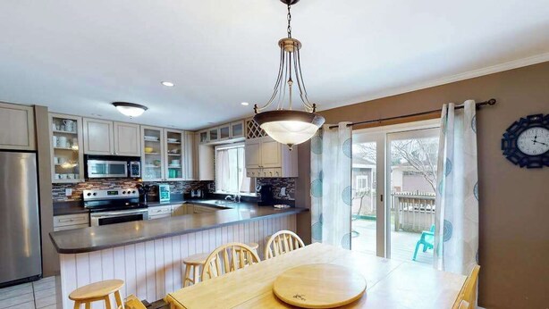 A kitchen with a central island, wooden chairs, a dining table, and a hanging light fixture. - Quiet Family Home 4 Blocks from the Beach/Boardwalk with Deck, WiFi & Fireplace (Ocean City)