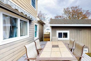 A wooden deck with a table and chairs, a small shed, and a house with windows. - Quiet Family Home 4 Blocks from the Beach/Boardwalk with Deck, WiFi & Fireplace (Ocean City)