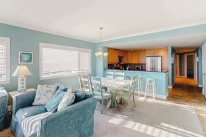 A compact living space with a dining area, kitchenette, and a sofa. - Ocean-view condo with shaded balcony, central AC, W/D, pool, gym & coastal decor (Ocean City)