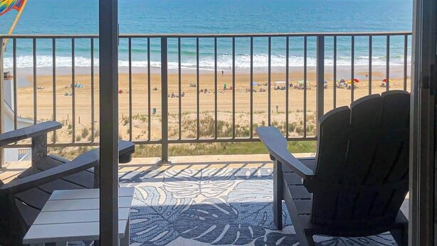 Ein Balkon mit Blick auf den Strand, eine Flagge und ein gemustertes Teppich.