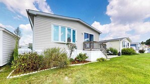 A mobile home with a front porch, a small garden, and a clear sky. - Assateague Pointe - Bay View Beauty (Berlin)