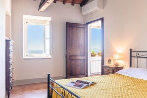 A bedroom with a bed, a window, a door, a nightstand, and a lamp. - Il Ponte - a romantic retreat blending history and panoramic views (Cortona)
