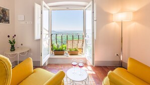 A room with a balcony, two yellow sofas, a small table with two wine glasses, and a lamp. - Il Ponte - a romantic retreat blending history and panoramic views (Cortona)