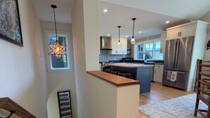 A modern kitchen with a central island, pendant lights, and a stainless steel refrigerator. - Cozy 1-bedroom apartment in Stowe with amazing views, AC & gas fireplace (Stowe)