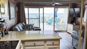 Ein Zimmer mit Küche, Essbereich, Sofa, Fernseher und Blick auf den Strand.
