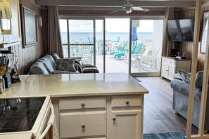 Ein Zimmer mit Küche, Essbereich, Sofa, Fernseher und Blick auf den Strand.