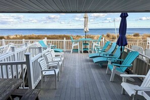 A covered deck with chairs and tables, overlooking the beach. - Beach Village 16 (Ocean City)