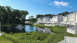 Et boligområde med en sø, hvide huse og en klar himmel.