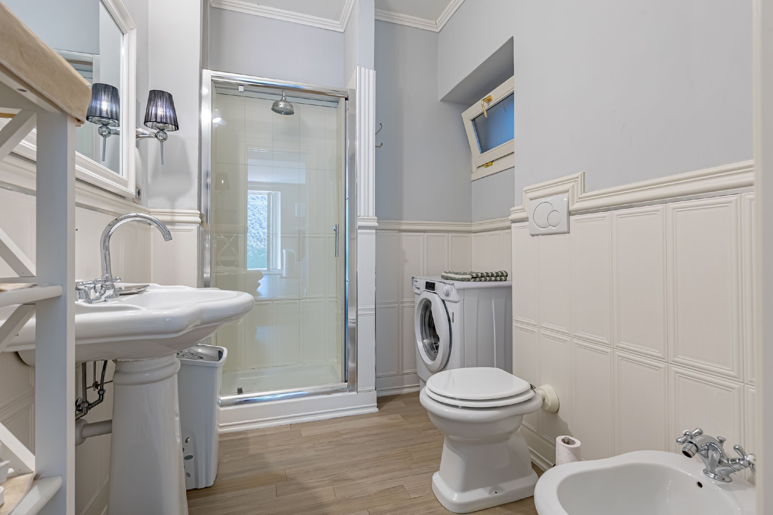 A bathroom with a sink, toilet, bidet, and a glass shower enclosure.