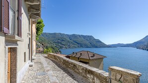 A stone-paved pathway leading to a building with a view of a lake and mountains. - Angela Lake View Apartment (Pognana Lario)