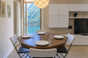 A dining area with a table set for four, a TV, and a view of a mountainous landscape.