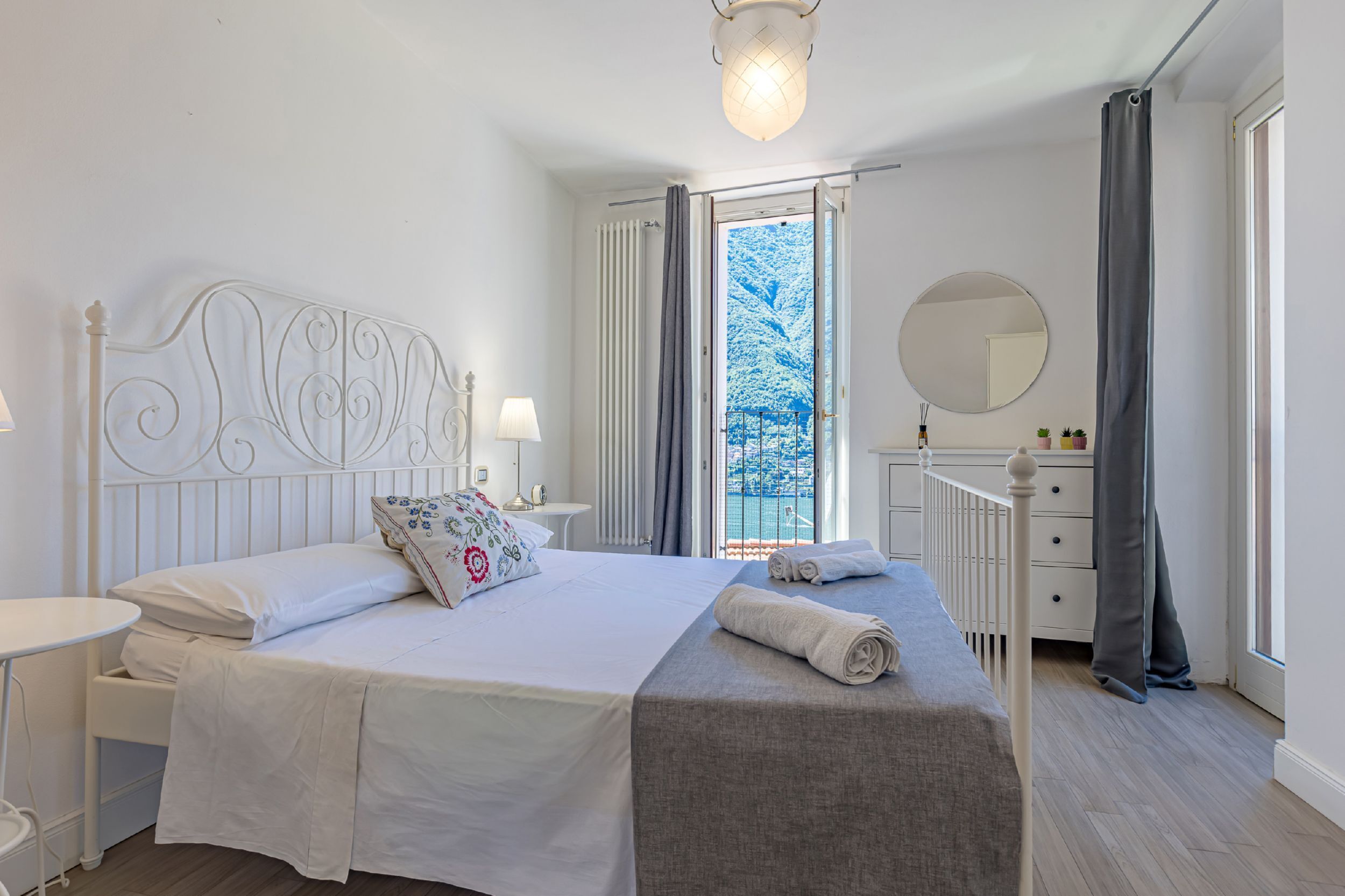 Une chambre d’hôtel avec un lit, une table de chevet, une lampe, une commode, un miroir et une vue sur un paysage enneigé par la fenêtre.