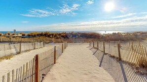 A sandy pathway leading to a beach with a wooden fence on both sides. - Beach Place N 3 (Ocean City)