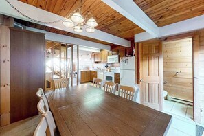 Un intérieur en bois comprenant une table à manger, des chaises et un coin cuisine.