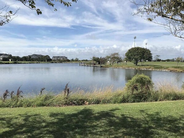 A calm lake with a dock, grassy areas, and trees. - 19th floor oceanfront getaway w/ pool access, private washer/dryer, and WiFi (Ocean City)