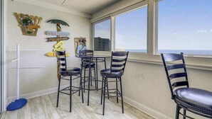 Een eethoek met uitzicht op de oceaan, met gestreepte stoelen en een ronde tafel.