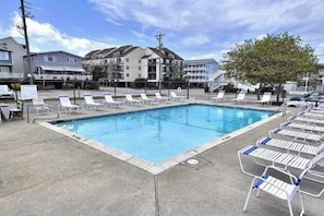 Ein Pool mit Liegestühlen, einer Betonplattform und mehrstöckigen Gebäuden im Hintergrund.