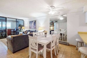 A modern living room with a dining area, a sofa, a ceiling fan, and a large window. - Recently Updated Condo in Oceanfront Complex w/Shared Pool, Free WiFi (Ocean City)