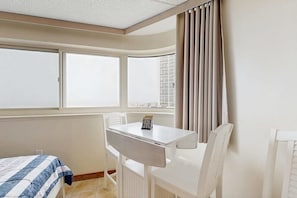 A room with a bed, a table, chairs, a window, and a curtain.