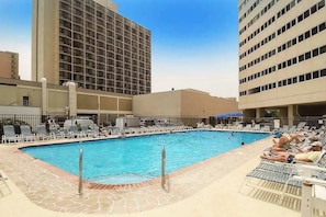 A swimming pool with lounge chairs and a tall building in the background.