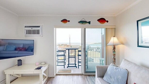 A room with a TV, a desk, a sofa, a balcony with chairs, and a view of the sea. - Assateague House 511 (Ocean City)