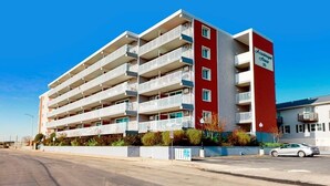A multi-story hotel with balconies, a red and white facade, and a clear blue sky. - Assateague House 511 (Ocean City)