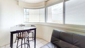 A room with a curved window, a dining table with chairs, and a cushioned bench. - Well-Appointed Vacation Getaway in Oceanfront Complex w/Shared Pool, Free WiFi (Ocean City)