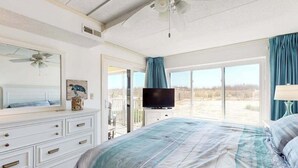Ein Schlafzimmer mit Bett, Fernseher, Kommode und einem Balkon mit Blick.
