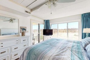 Ein Schlafzimmer mit Bett, Fernseher, Kommode und einem Balkon mit Blick.