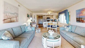 Ein Wohnzimmer mit zwei Sofas, einem Couchtisch und einem Essbereich mit Stühlen und einem Tisch.