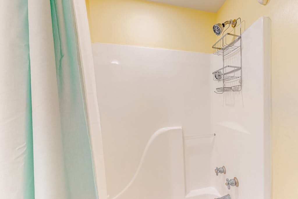 A bathroom with a white bathtub, a shower, and a towel rack.