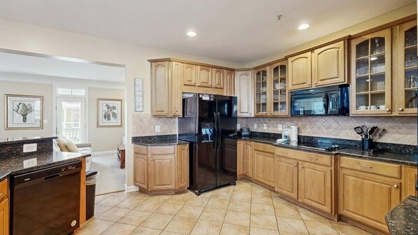 A kitchen with wooden cabinets, a black refrigerator, a microwave, and a dishwasher. - Beautiful home in Bayside complex with pool, washer/dryer, & free WiFi (Ocean City)