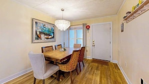 A dining room with a wooden table, wicker chairs, a chandelier, and a painting on the wall. - Oceanfront Tide's Edge condo with balcony & boardwalk - walkable locale (Ocean City)