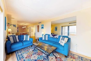 Ein Wohnzimmer mit zwei blauen Sofas, einem Couchtisch und einem Teppich mit Muster.