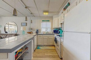 Eine Küche mit weißen Schränken, einer Marmorarbeitsplatte, einem Spülbecken und einem Kühlschrank.