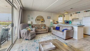 Ett modernt vardagsrum med en soffa, ett soffbord och en matplats med en köksö.