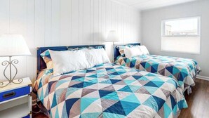 A bedroom with two beds, a nightstand, a lamp, and a window. - 3rd-floor condo near the beach with balcony, partial ocean views, & central AC (Ocean City)