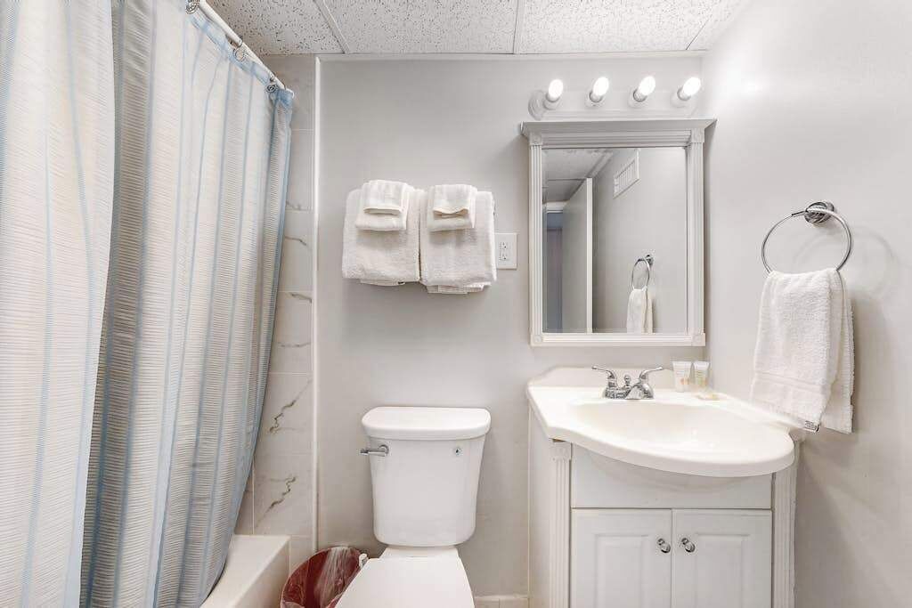 Ein Badezimmer mit Toilette, Waschbecken, Spiegel und Handtuchhalter.