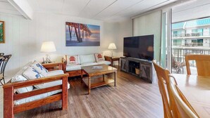 A living room with a sofa, coffee table, TV, and fireplace. - 3rd-floor condo near the beach with balcony, partial ocean views, & central AC (Ocean City)