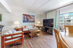 A living room with a sofa, coffee table, TV, and fireplace. - 3rd-floor condo near the beach with balcony, partial ocean views, & central AC (Ocean City)