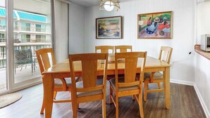 A dining area with a wooden table and chairs, a chandelier, and two paintings on the wall. - 3rd-floor condo near the beach with balcony, partial ocean views, & central AC (Ocean City)