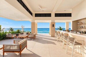 Ein moderner Außenbereich mit Bar, Sitzgelegenheiten und Meerblick.