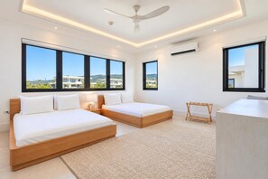 Ein modernes Hotelzimmer mit zwei Betten, einem Deckenventilator, großen Fenstern und Blick auf die Landschaft.