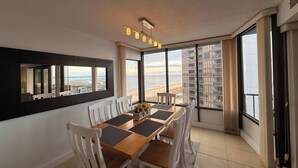 A dining area with a view of the ocean, a large window, and a modern chandelier. - Upscale ocean view condo with pool access & balcony - walk to beach, restaurants (Ocean City)