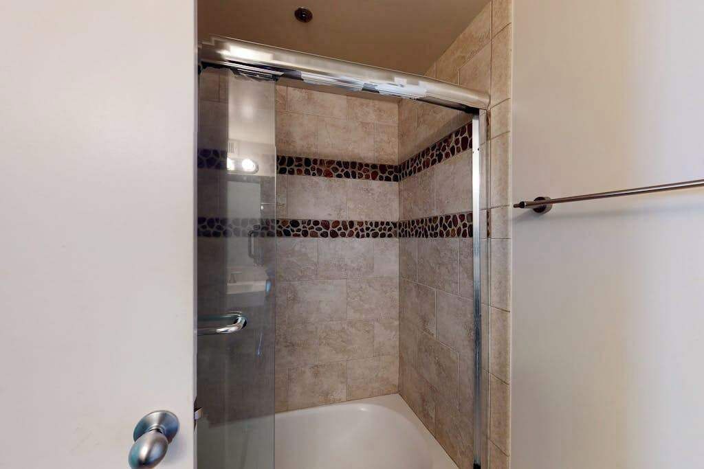 A glass-enclosed shower with a glass door, tiled walls, and a metal towel rack.